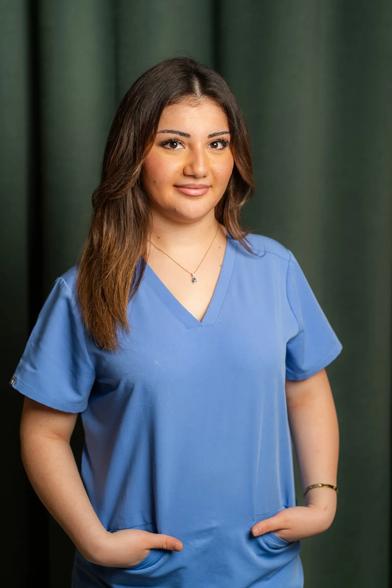 Porträt von Delila Yaman, Dentalassistentin in Ausbildung im Zahnärztehaus Zürich in blauer Praxisbekleidung.