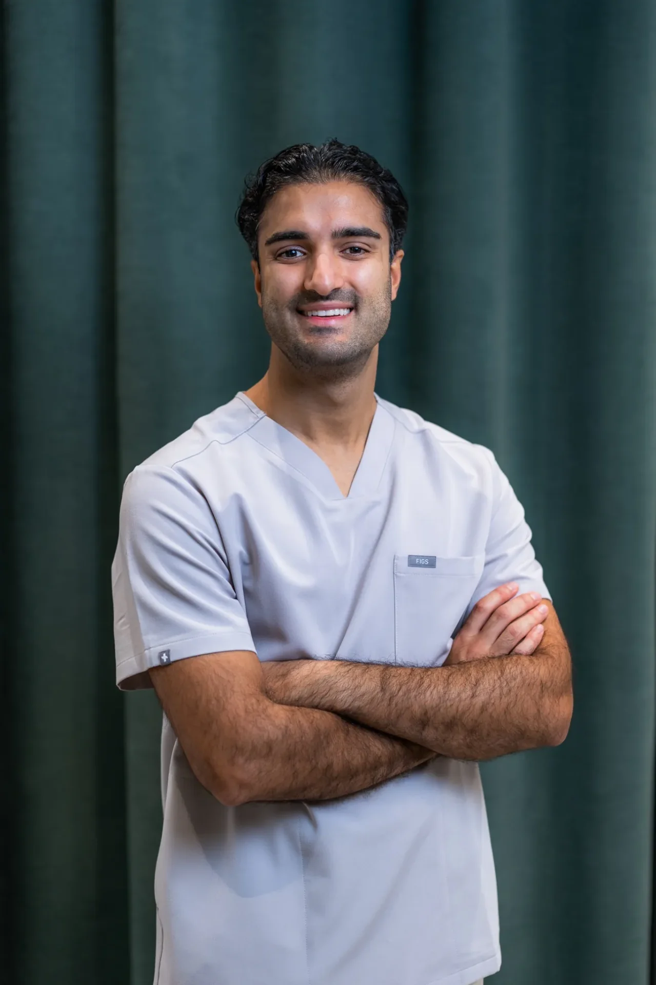 Porträt von Dr. Nojan Khalili im Zahnärztehaus Zürich in grauer Praxisbekleidung.