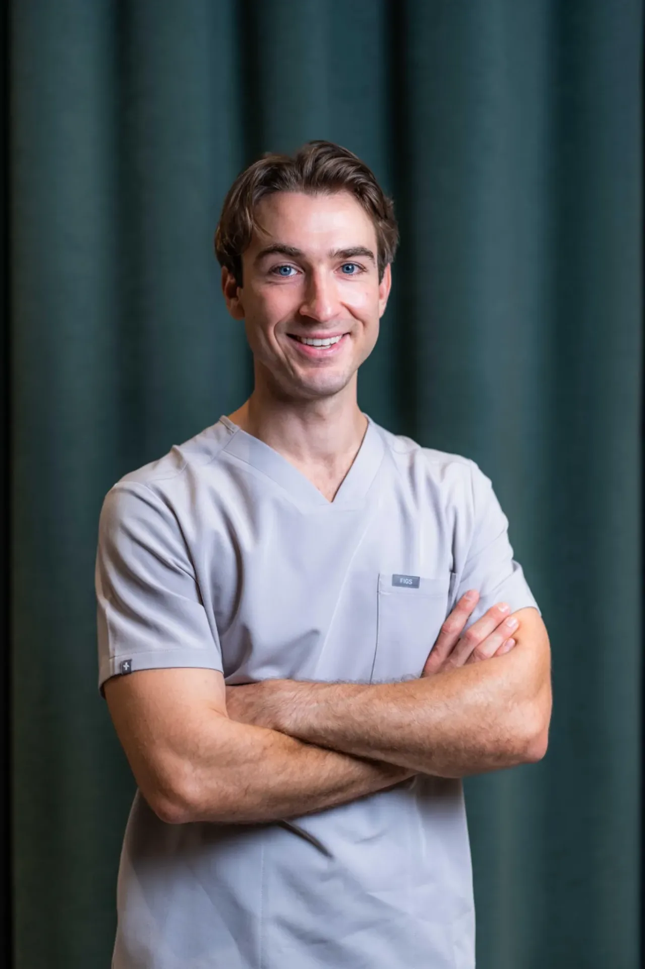 Porträt von Dr. med. dent. Philipp Meyer, Kieferorthopäde in Zürich, im Zahnärztehaus Zürich in grauer Praxisbekleidung.